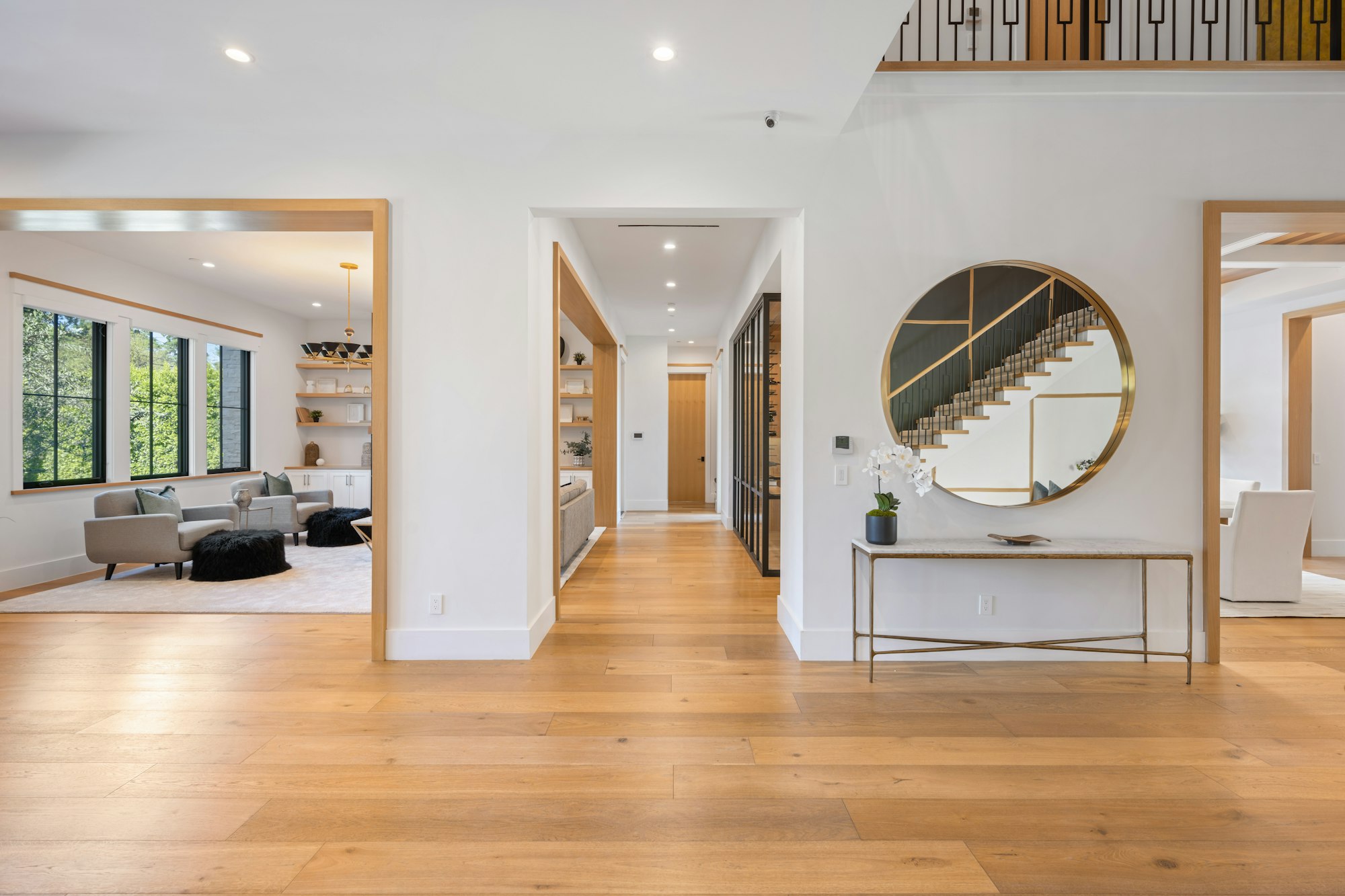 the foyer is very large and clean with white walls, wood floors, a circular